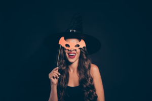 Woman holding up a bat mask and smiling wide